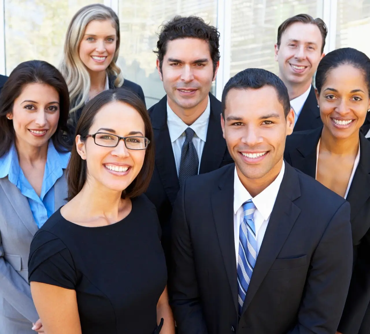 A diverse group of smiling business professionals posing together.