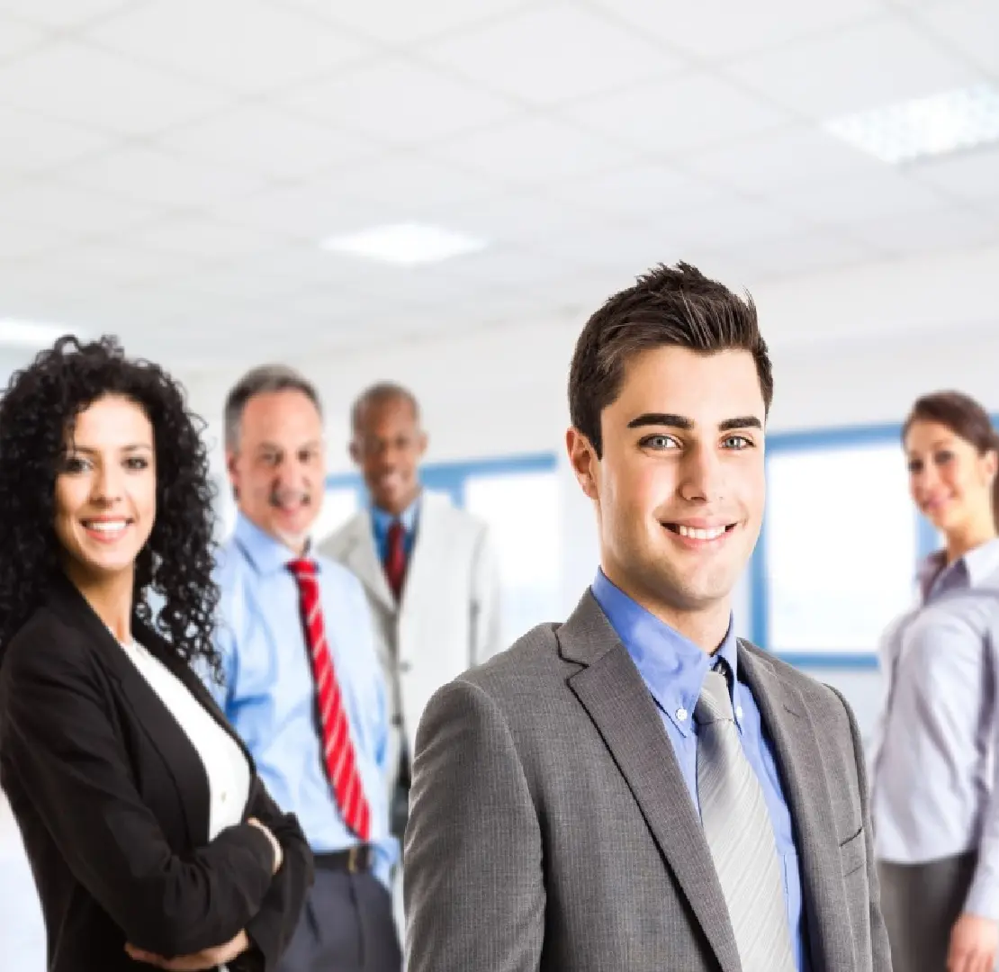 A group of five professionally dressed businesspeople smiling.
