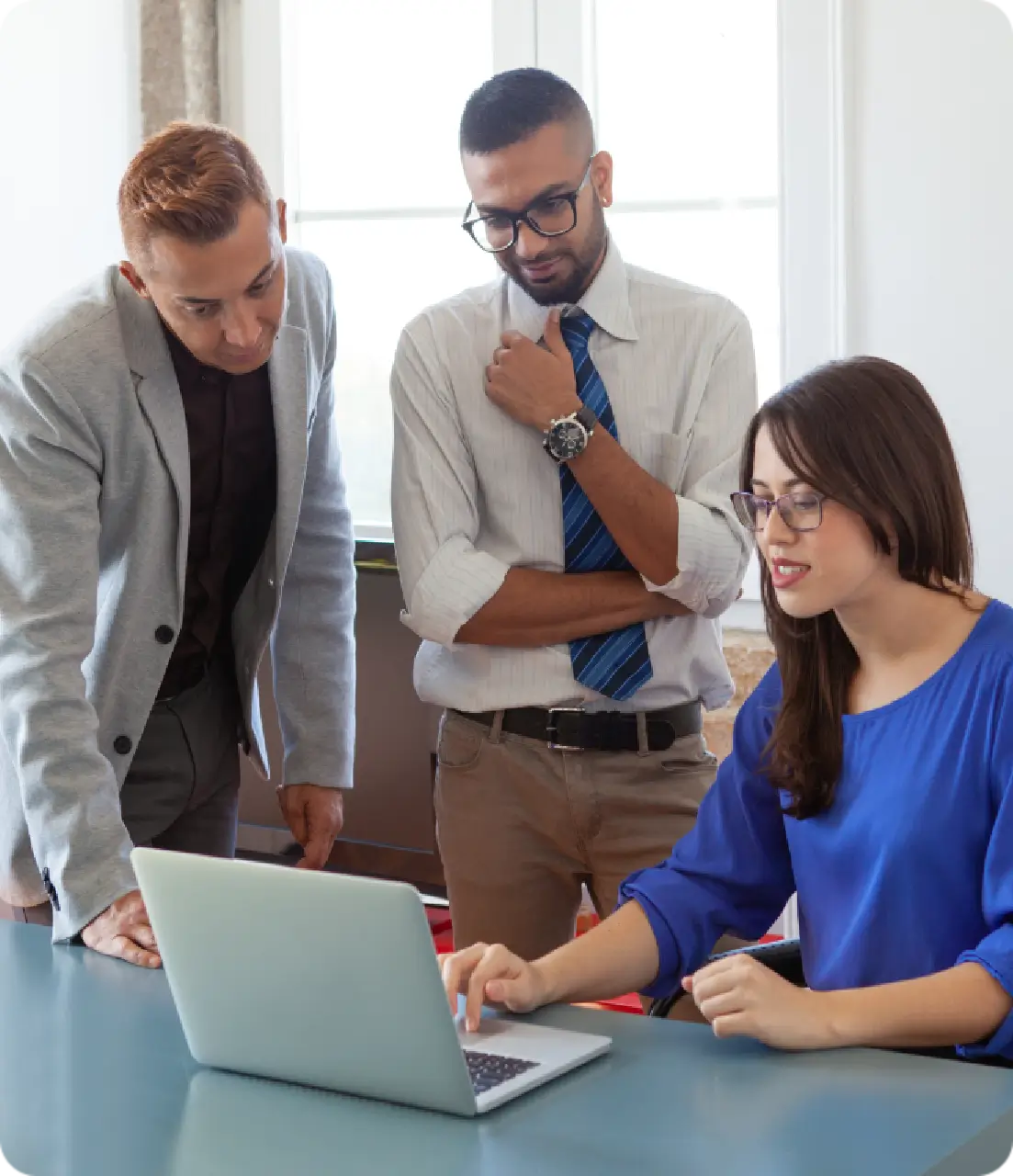 Three colleagues discussing work on laptop.